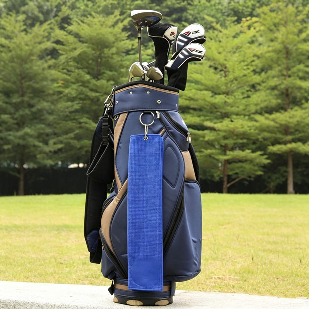 Eliteshine golf towel clipped to navy golf bag on course — waffle cotton trifold towel with carabiner attachment